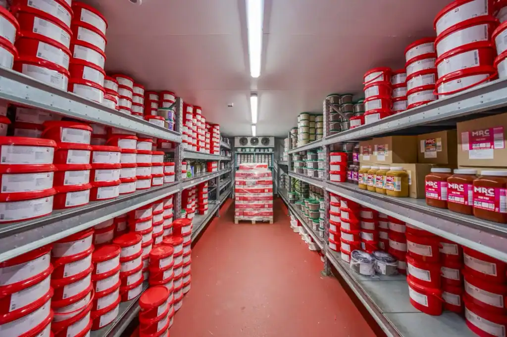 Cold store aisle shelved with red tubs of sauces, glazes and marinades
