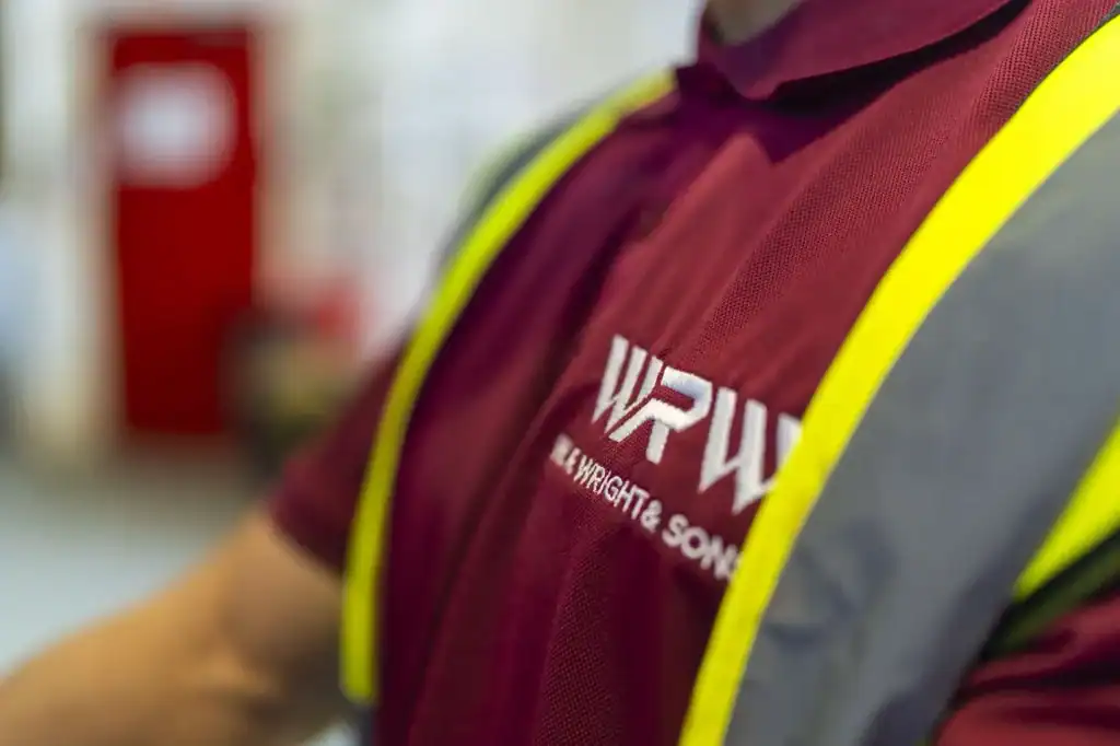 Close-up of a W.R. Wright & Sons branded polo shirt worn under a hi-vis vest