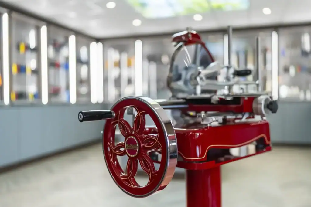 A restored red Metcalfe hand-cranked meat slicer on display in the knife showroom