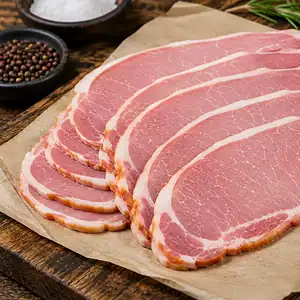 Slices of cured back bacon fanned out on parchment, with bowls of salt and peppercorns alongside