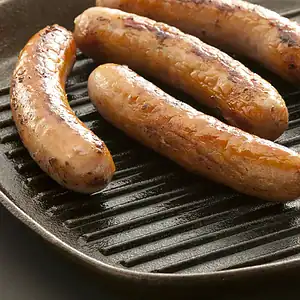 Sausages browning on a ridged cast iron griddle pan