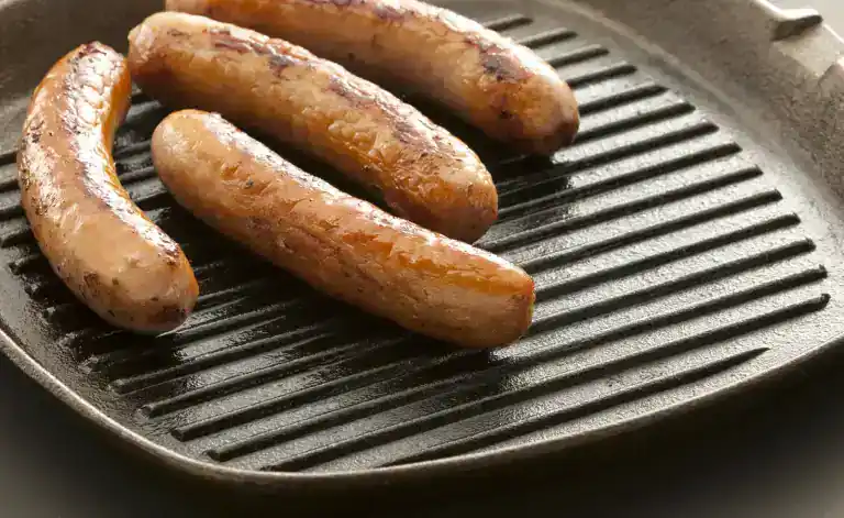 Sausages browning on a ridged cast iron griddle pan