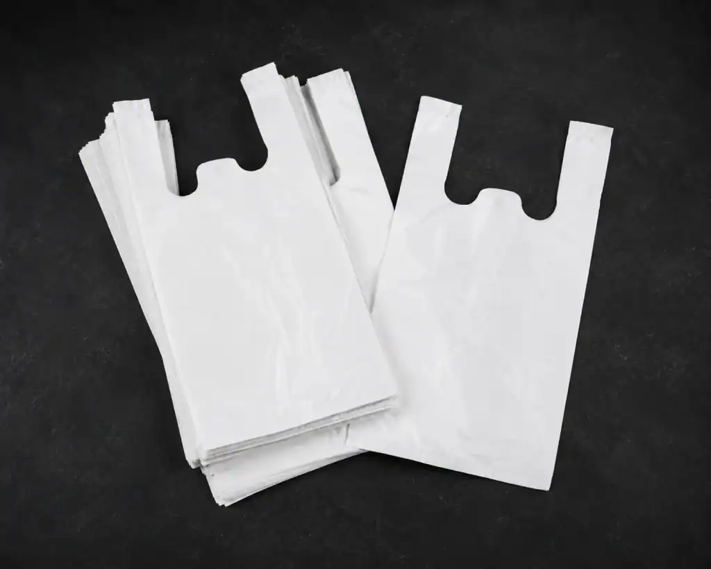 Plain white vest carrier bags, a single bag laid over a folded stack