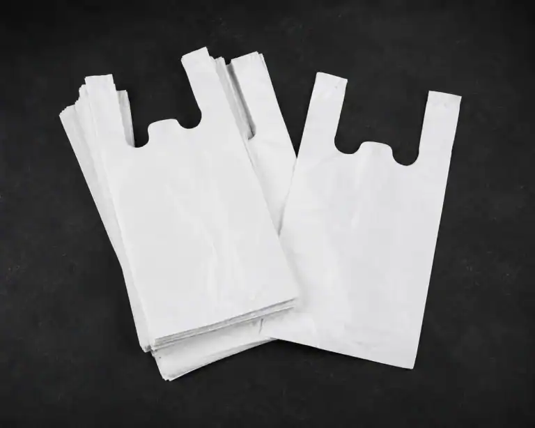 Plain white vest carrier bags, a single bag laid over a folded stack