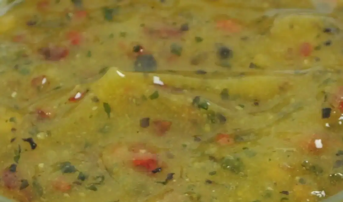 Close-up of RAPS Ginger, Chilli and Lime marinade, a pale gold paste with red chilli and herb pieces