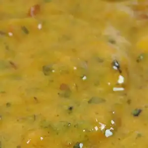 Close-up of RAPS Lemon and Chilli marinade, a golden paste flecked with herbs and chilli