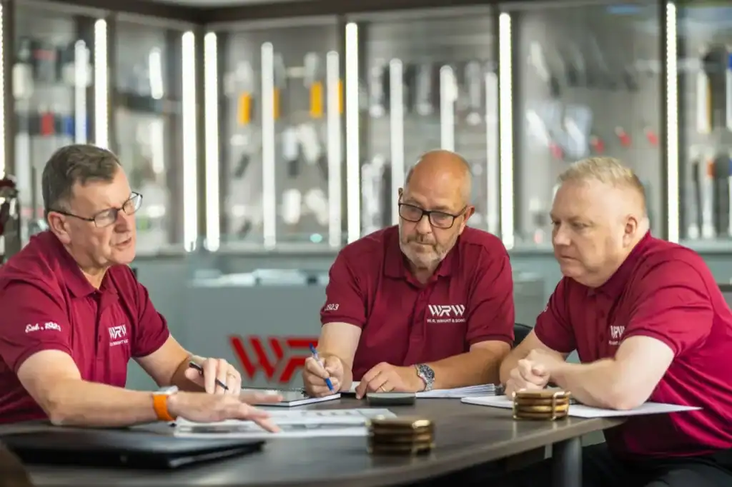 Three members of the W.R. Wright & Sons team in branded polo shirts, going through paperwork at a table in the showroom