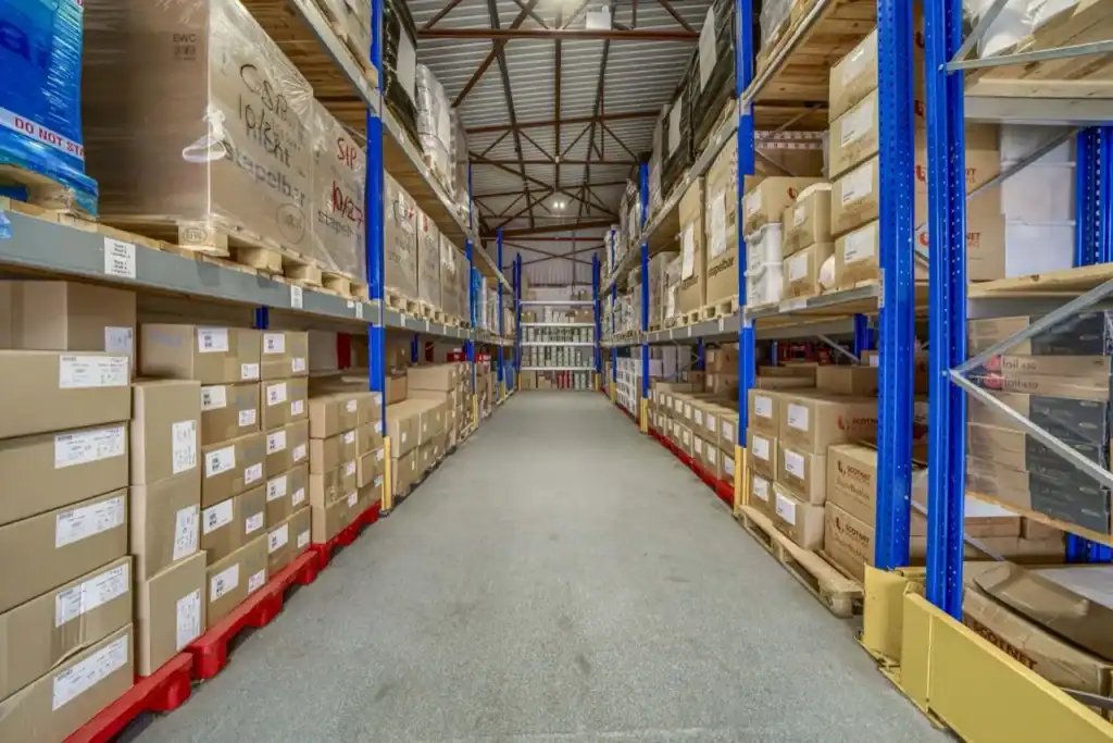 Warehouse aisle with blue pallet racking holding boxed and shrink-wrapped stock