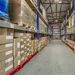Warehouse aisle with blue pallet racking holding boxed and shrink-wrapped stock