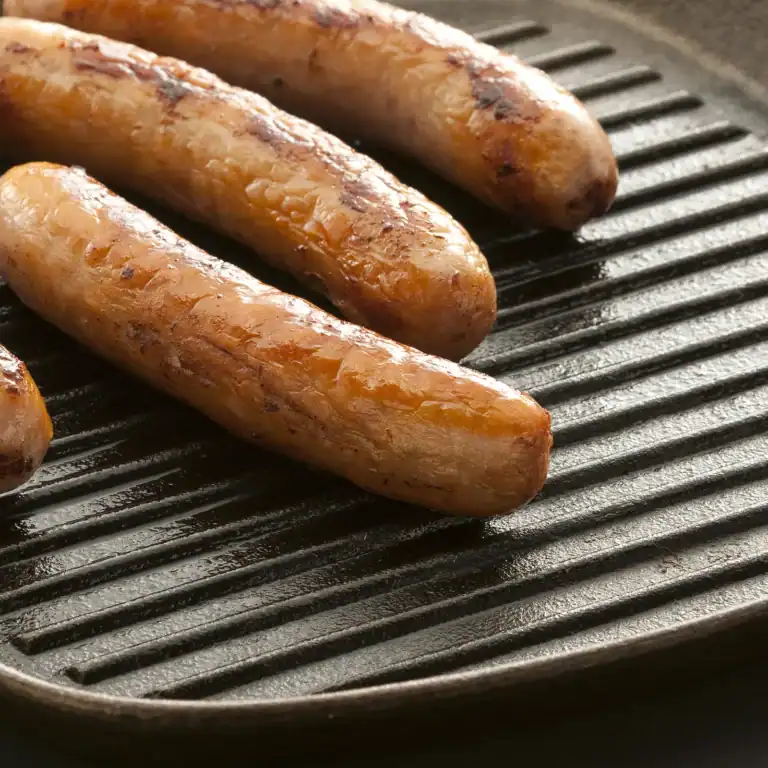 Sausages browning on a ridged cast iron griddle pan