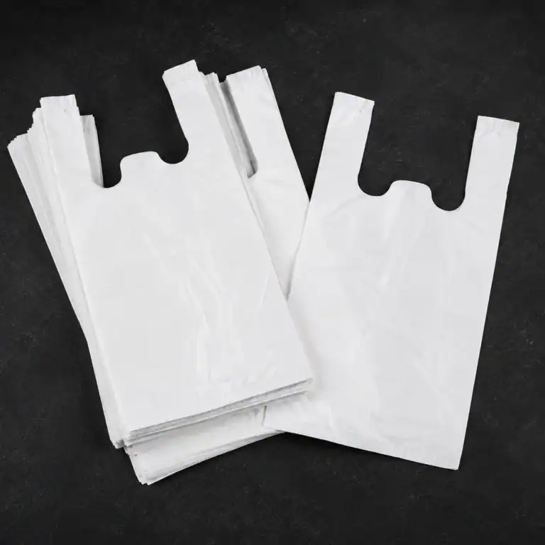 Plain white vest carrier bags, a single bag laid over a folded stack