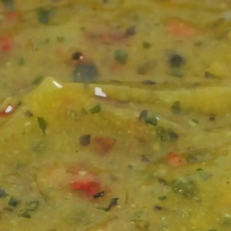 Close-up of RAPS Ginger, Chilli and Lime marinade, a pale gold paste with red chilli and herb pieces